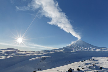 Vue hivernale de l& 39 éruption active du volcan Klyuchevskoy (Klyuchevskaya Sopka) et des rayons du soleil sur un beau ciel bleu le jour glacial. Beau paysage volcanique de la péninsule du Kamtchatka en Extrême-Orient russe.