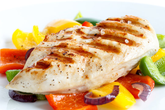 Detail of whole seasoned grilled chicken breast on roasted peppers.