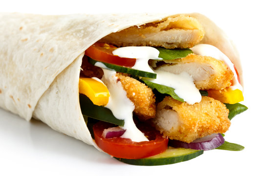 Detail of crumbed fried chicken and salad tortilla wrap with white sauce.