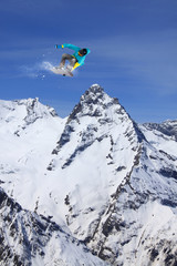 Naklejka na ściany i meble Snowboarder jumping on mountains. Extreme snowboard freeride sport.