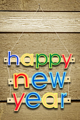 Hanging greeting text Happy New Year on wooden background