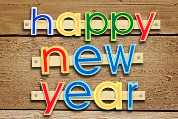 Nailed greeting text Happy New Year on brown wooden background