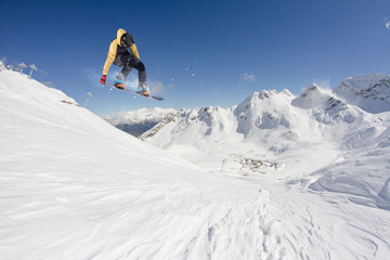 Snowboarder jumping on mountains. Extreme snowboard freeride sport.