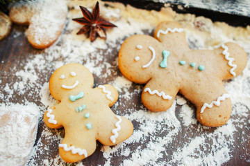 Obraz na płótnie Canvas Gingerbread men on floured table, close-up. Preparing of traditional Christmas treat. Homemade bakery, xmas sweet, winter holidays concept