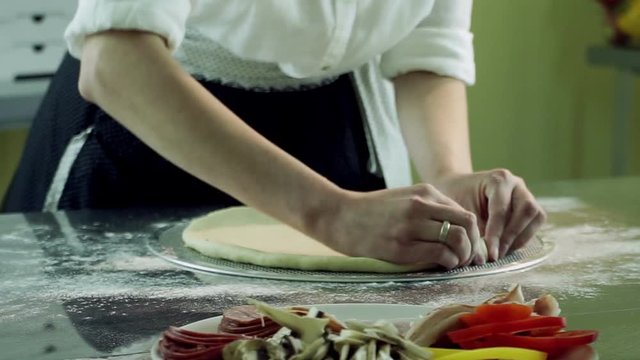 Cooking pizza. Female hands kneading dough and preparing a pizza base. Close-up shot. HD