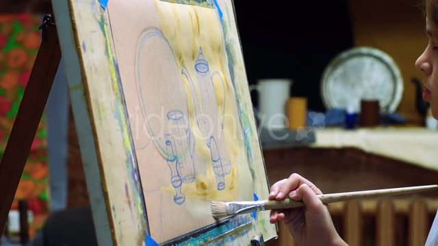 Schoolgirl painting a picture in studio