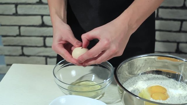 Separating yolk and white of the white shell egg with woman hands 