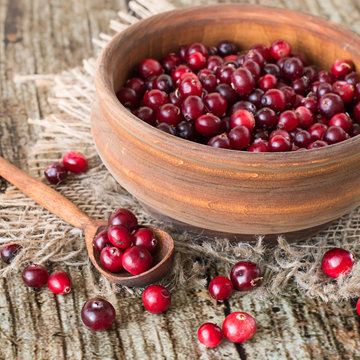  Cranberries.   Cranberries in a wooden bowl and in a spoon on burlap on an old wooden table.