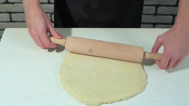 female hands taking rolling pin for making dough on board