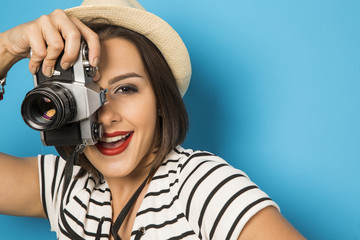 Fashion young girl makes the photo with old camera. Blue backgro