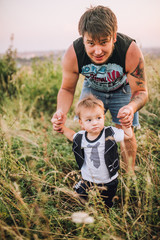 Fototapeta premium happy joyful father having fun throws up in the air his small child, family, father's day - concept. On the nature near the old retro car. Man has tatoo