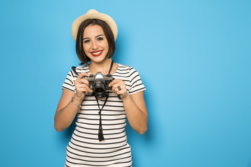 Fashion young girl makes the photo with old camera. Blue backgro