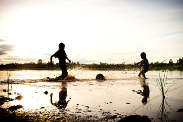 Silhouette of boy playing football in water