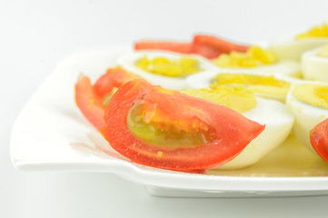 tomatoes and boiled eggs on a white plate