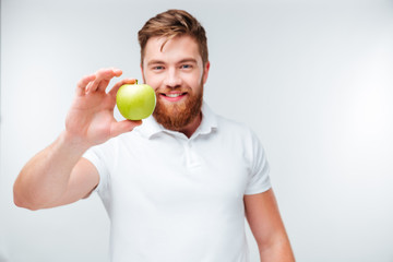 Casual bearded man holding green apple and looking at camera