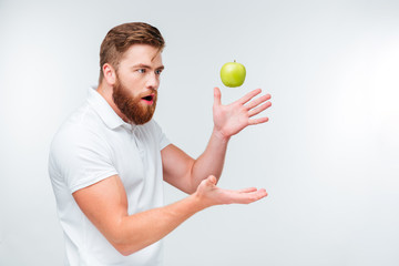 Funny bearded man throwing up a green apple