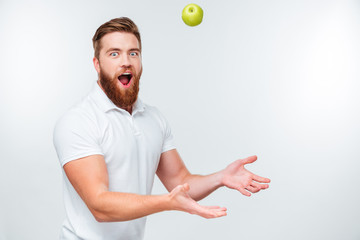 Portrait of handsome funnny bearded man throwing apple up