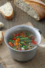 zuppa di verdure in tazza di metallo sfondo tavolo di cucina rustico