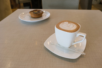 hot fresh coffee in white glass with tree shape of heart foam blueberry tart fruit pie on wooden table at sunset at coffee time / hot fresh coffee blueberry pie