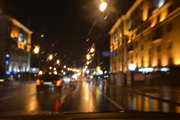 Fototapeta na wymiar Drops of rain on the window of the car, the lights of the night