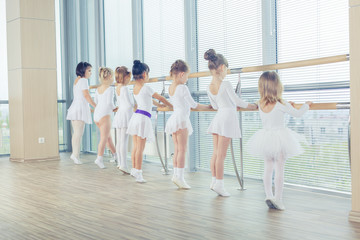 Group of seven little ballerinas standing in row and practicing 