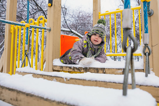 Boy is crawling on the winter playground
