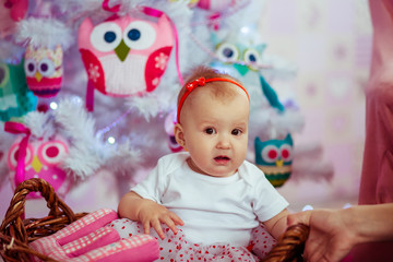 Funny girl sits in the basket before a Christmas tree made of to