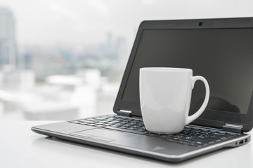 Fototapeta premium White coffee cup is on the black laptop - Time to break