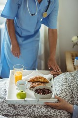 Nurse serving breakfast to senior woman