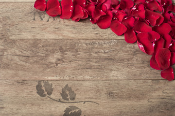 Red rose petals on the wooden background. Border on a wooden table. Top view, copy space. Floral frame. Styled marketing photography. Wedding, gift card, valentine's day or mothers day background