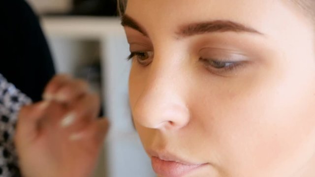 makeup artist gets tone on the skinof the model in the Studio