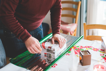 Close up on hands of young man wrapping christmas present - christmas, holiday concept