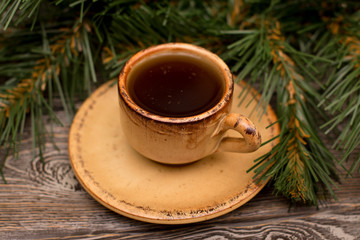 Obraz na płótnie Canvas Small cup of coffee and fir branch on wooden background