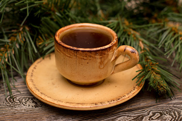 Small cup of coffee and fir branch on wooden background