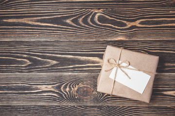 Vintage gift box with blank tag on old wooden background.