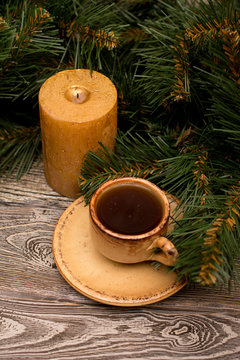 Small cup of coffee, candle and fir branch on wooden background