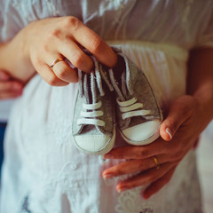 Closeup of grey keds for newborn held by a woman before her bell