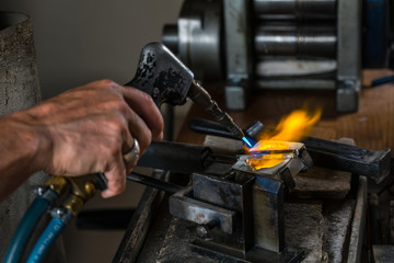 Close-up of Silver Casting from Crucible to Metal Mold with blowtorch; Goldsmith Workshop;