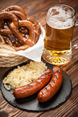Pretzels, bratwurst and sauerkraut on wooden table