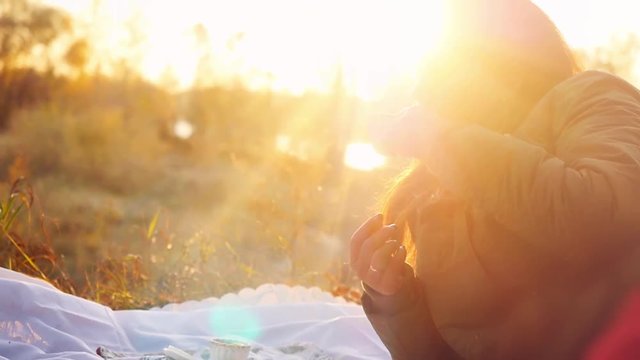 Young beautiful woman having hot tea at sunset lying relaxing and enjoying nature scene in slowmotion. 1920x1080