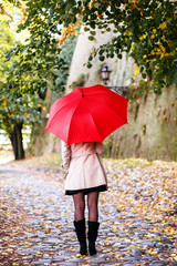 Obraz premium Rear view of young woman with red umbrella.