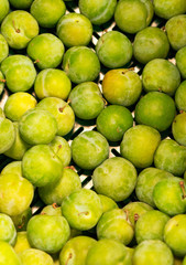 Lots of bright green plums in supermarket.