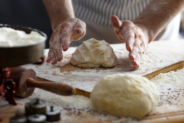 Close up of male baker hands kneading the dough with flour powder.
