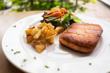 salmon steak with roast potato and salad