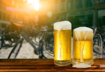 cold mug of beer with foam on the background of the street
