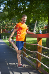 Fit runner man outdoor. Full length shot of young man at park after running relaxing and stretching. 