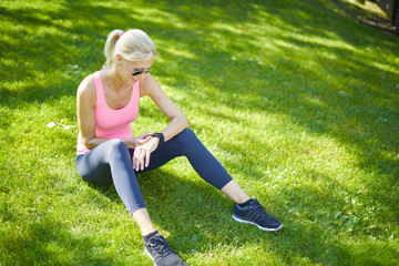 Woman after morning running. Full length shot of a beautiful fit woman watching her sport watch and checking running app.