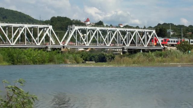 Электричка проходит по железнодорожному мосту через реку