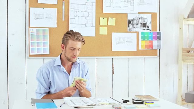 Successful architector holding money sitting at workplace Slow motion