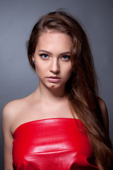 Portrait of the teenager in a red dress on a gray background